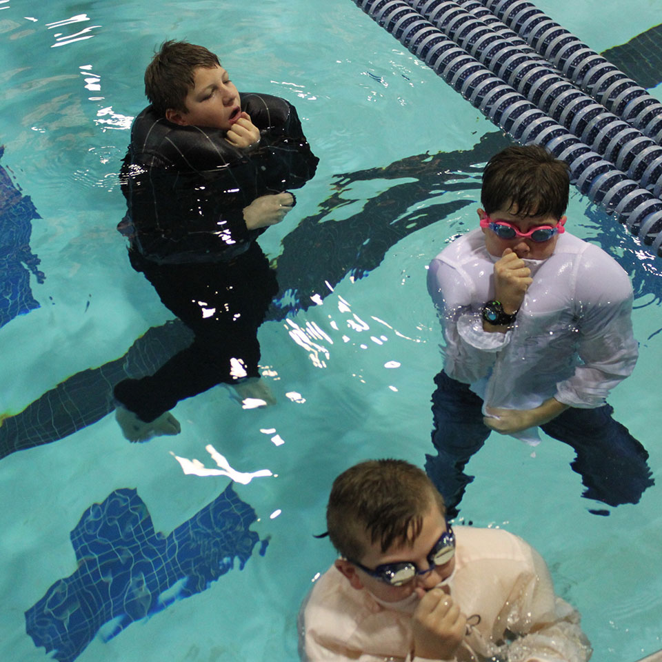 Children attend drown-proofing class in a swimming pool.