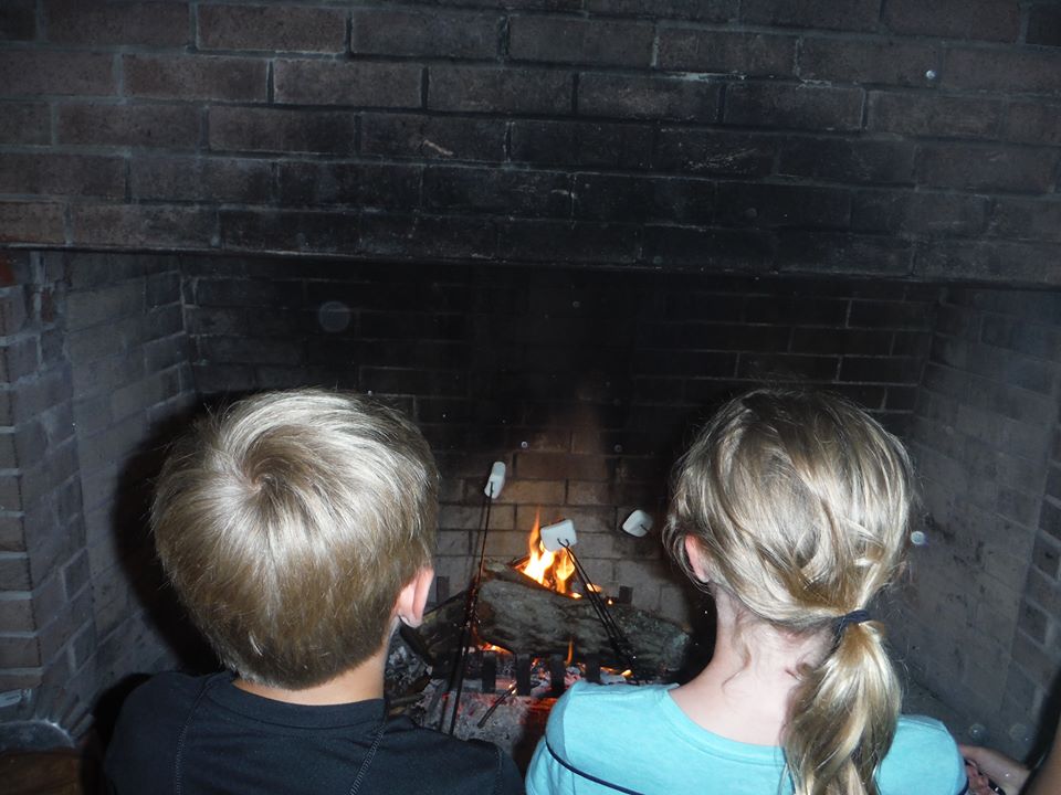 Two campers roasting marshmallows over a camp fire. 